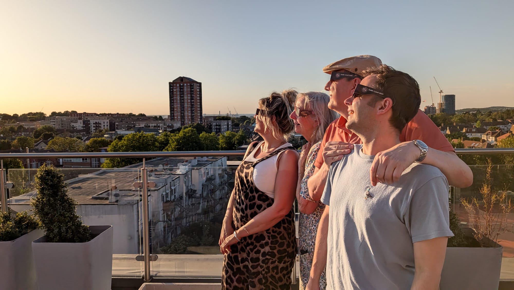 four people with eclipse glasses watching the Sun on a terrace